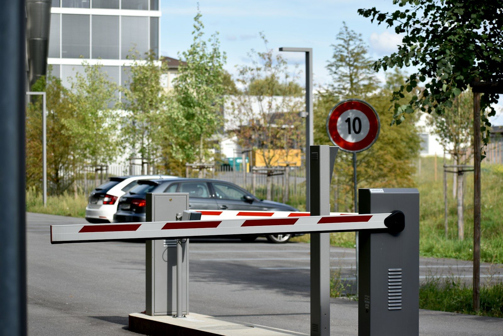 A parking barrier lowered across the lane beside a speed limit sign showing 10. Photo by Mauro Sbicego on Unsplash