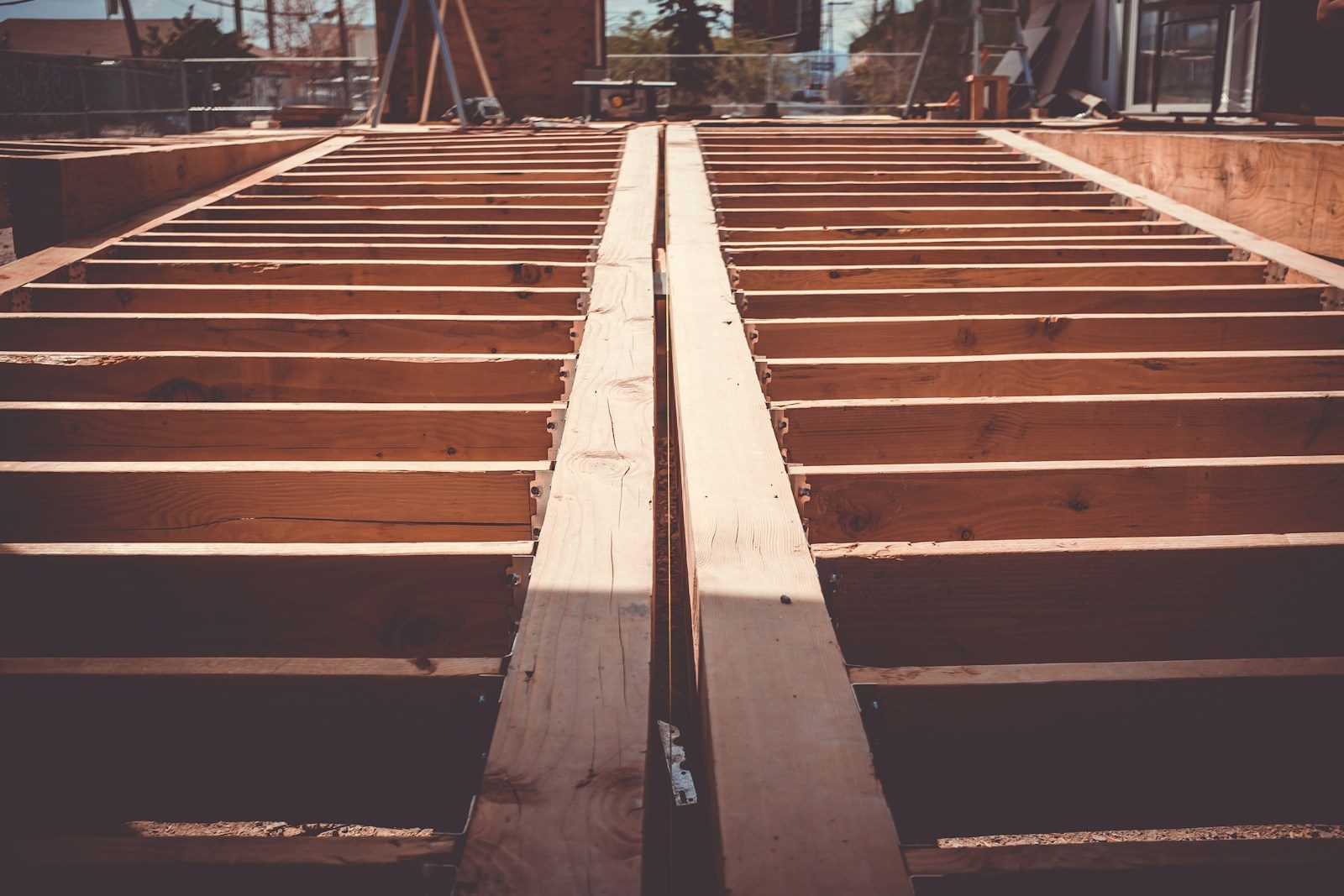 Open floor joists on a building site, the floor laid before anything stands on it. Photo by Quilia on Unsplash